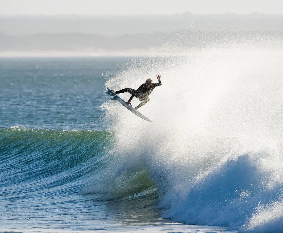 Surfer carving a wave on a performance surfboard with FCS II compatible fins