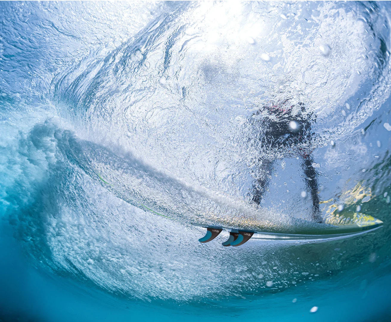 Surfer riding a wave from an underwater perspective

